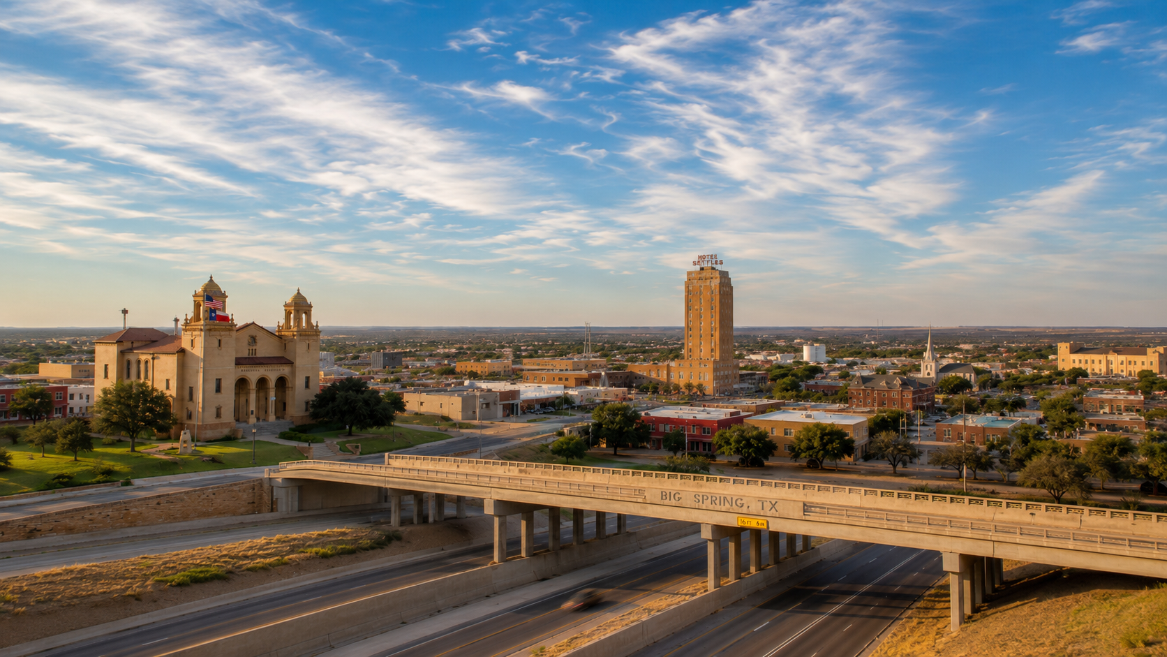 Downtown Big Spring, Texas skyline at sunset with the Hotel Settles tower, Sacred Heart Catholic Church, and the "Big Spring, TX" overpass sign